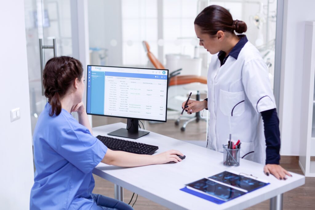 stomatolog-nurse-tooth-clinic-checking-patient-appointment-looking-computer-monitor-stomatology-assistant-teeth-doctor-discussing-reception-dental-office (1)